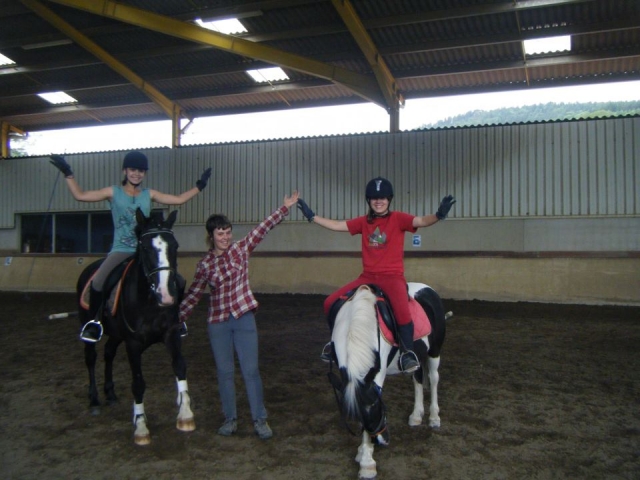  Two girls riding ponies with hands up 